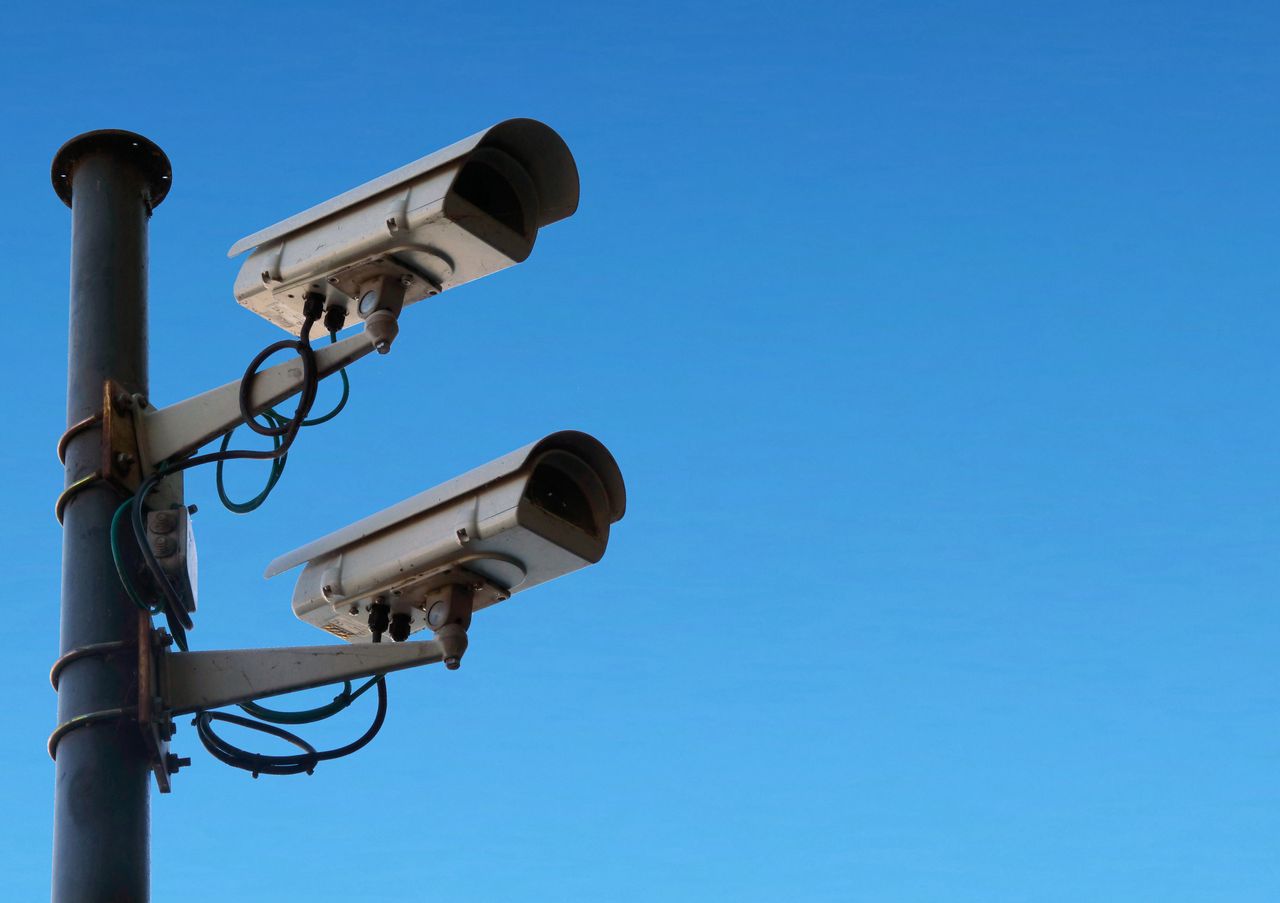 product-03 Low angle of security camera attached to black post located isolated on blue sky on sunny day in daytime outside